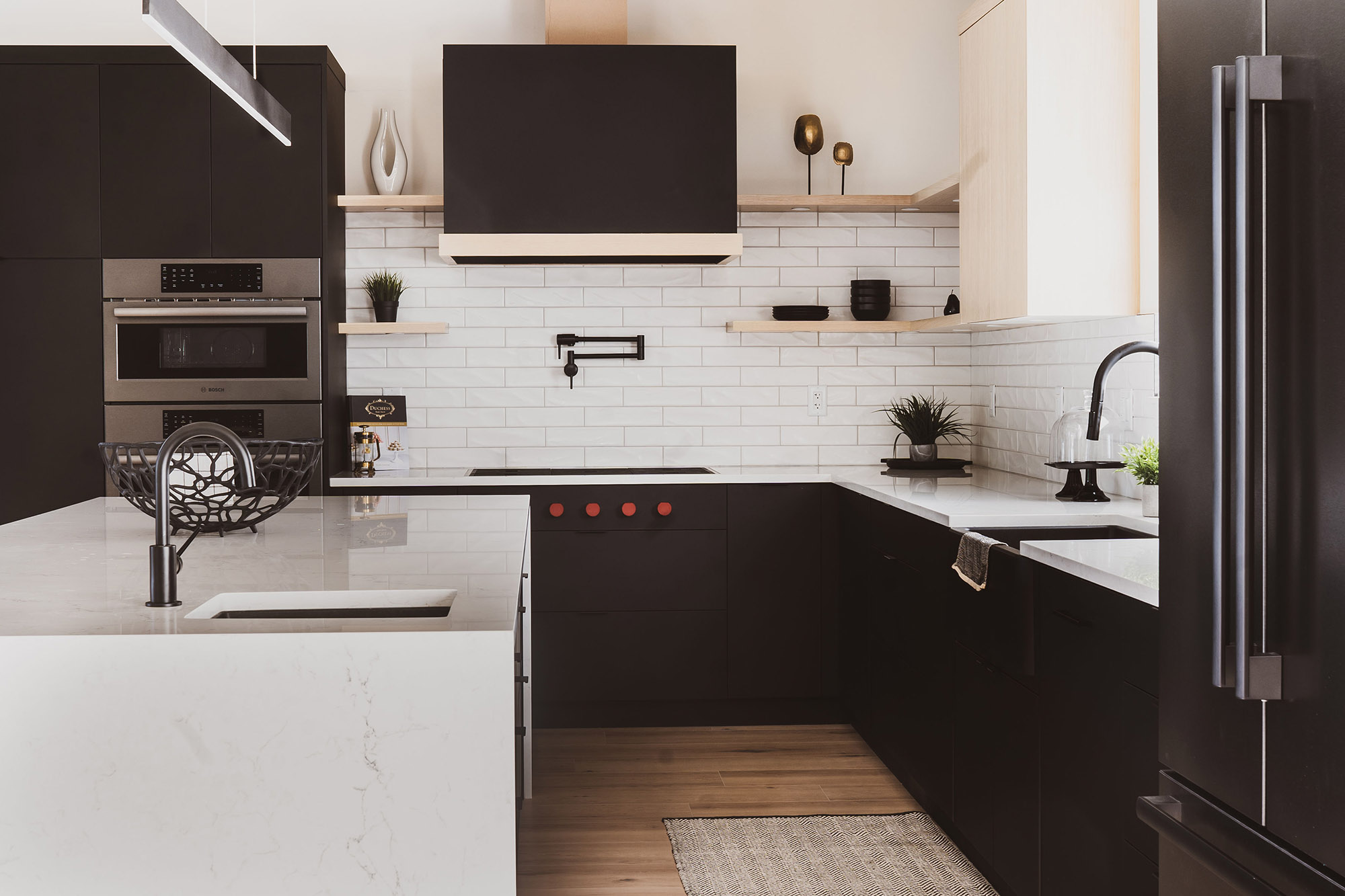 Modern matte black kitchen cabinetry with white subway tile and quartz waterfall island