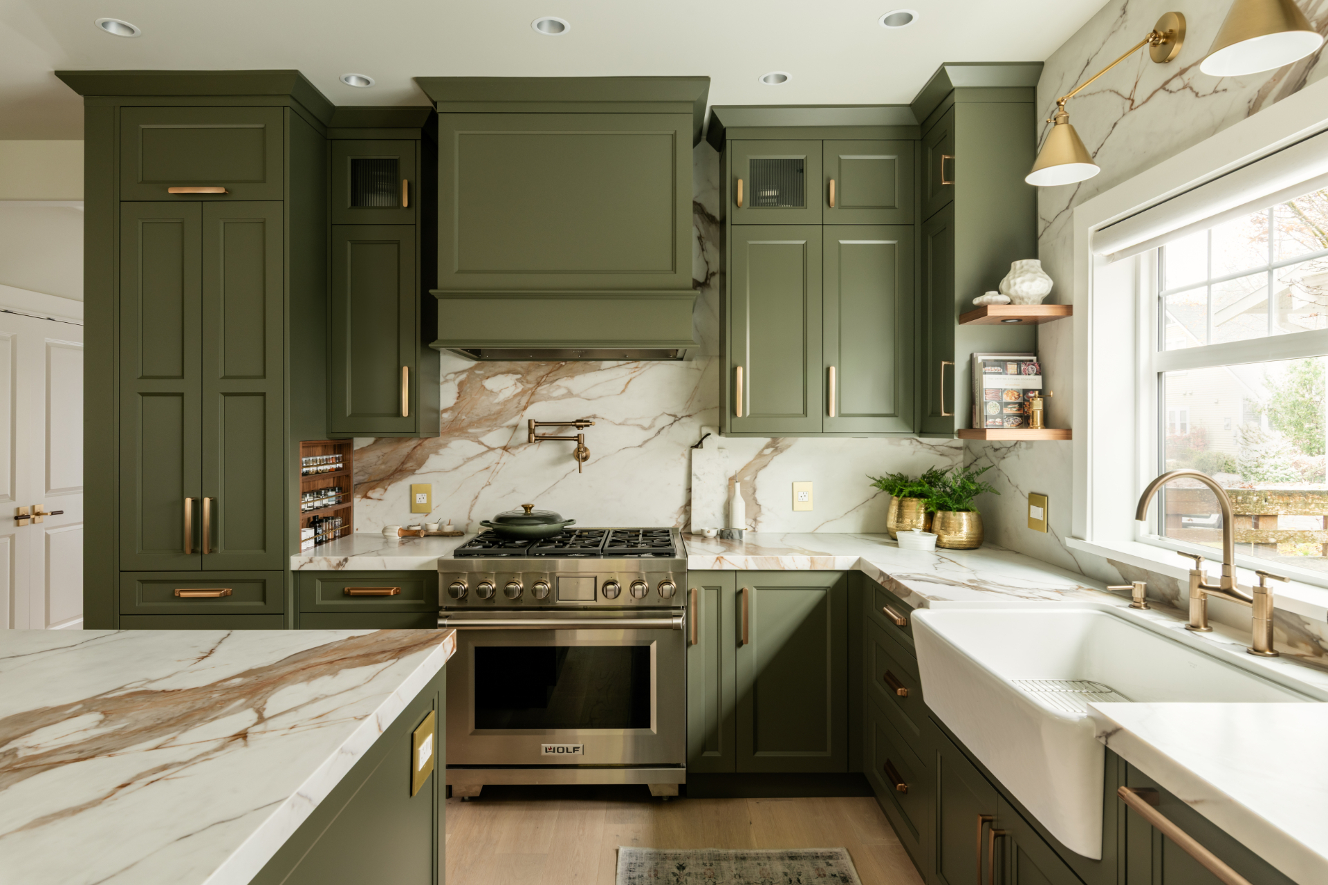 Sage green cabinetry kitchen with brass hardware and marble backsplash by Harbour City Kitchens