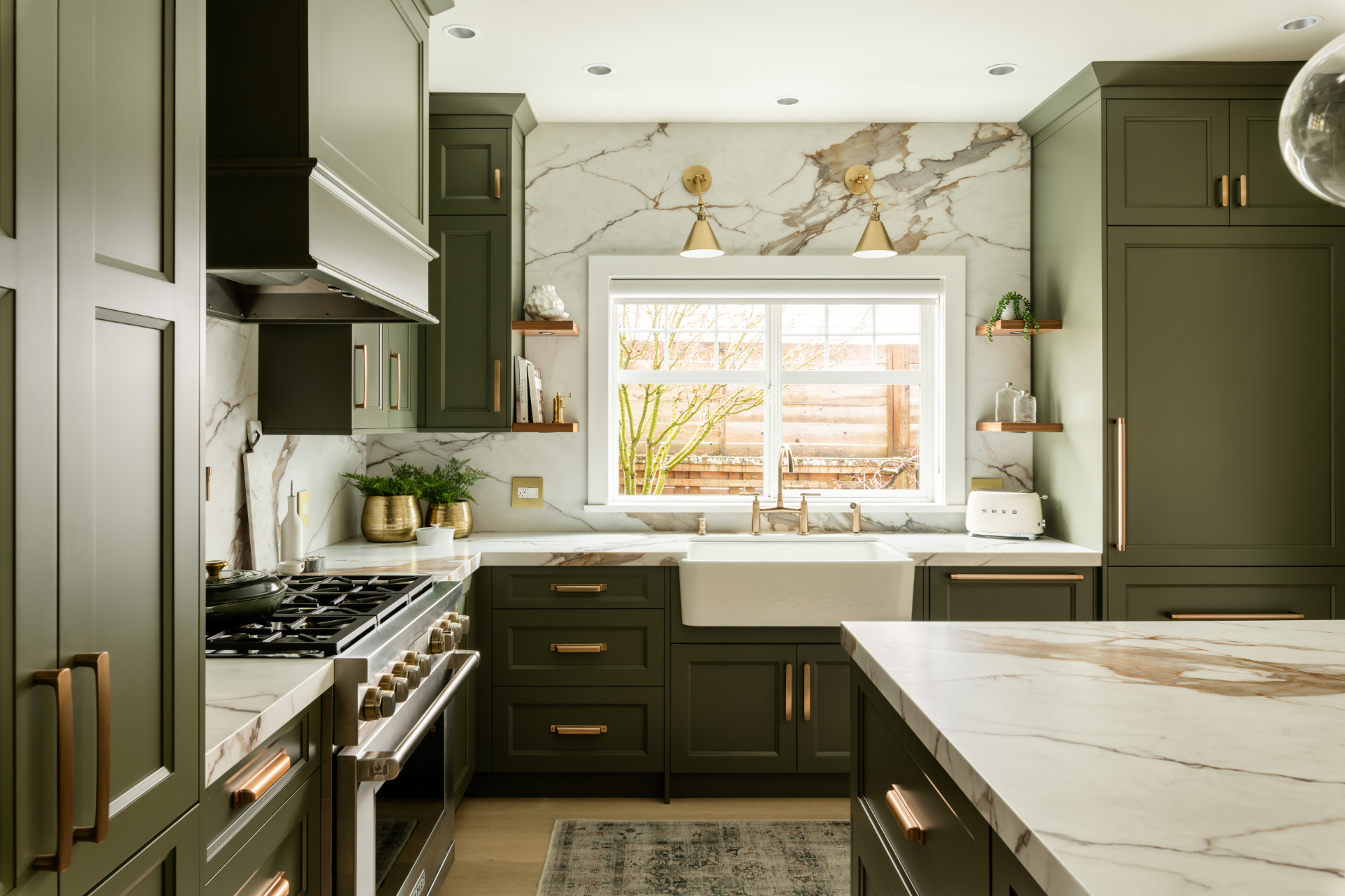 Sage green kitchen with calacatta marble backsplash, farmhouse sink, and brass fixtures by Harbour City Kitchens